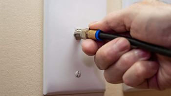 A hand is screwing a light switch on a wall